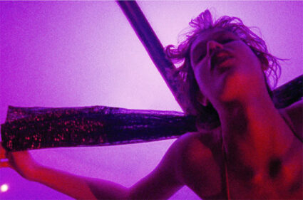 Still frame from Gaspar Noe's psychedelic feature Enter the Void, showing a short-haired woman who looks to be writhing in ecstasy on a cross