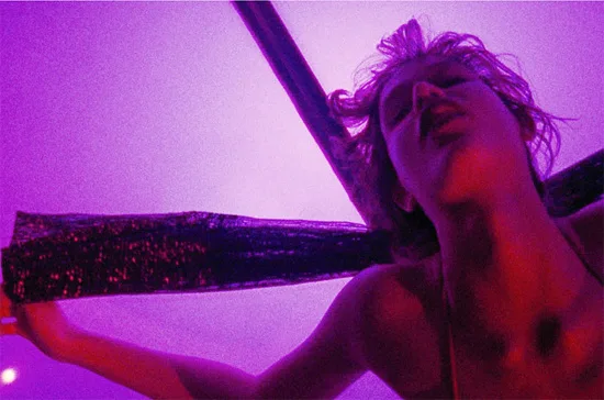 Still frame from Gaspar Noe's psychedelic feature Enter the Void, showing a short-haired woman who looks to be writhing in ecstasy on a cross