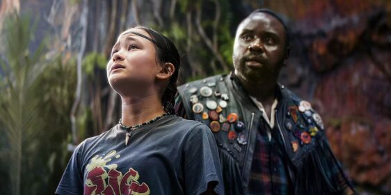 Screencap of Kaylee Hottle and Brian Tyree Henry in "Godzilla x Kong: The New Empire." Hottle is in the foreground looking up. Henry is positioned behind her, his eyeline about to follow hers.