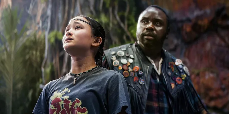 Screencap of Kaylee Hottle and Brian Tyree Henry in "Godzilla x Kong: The New Empire." Hottle is in the foreground looking up. Henry is positioned behind her, his eyeline about to follow hers.